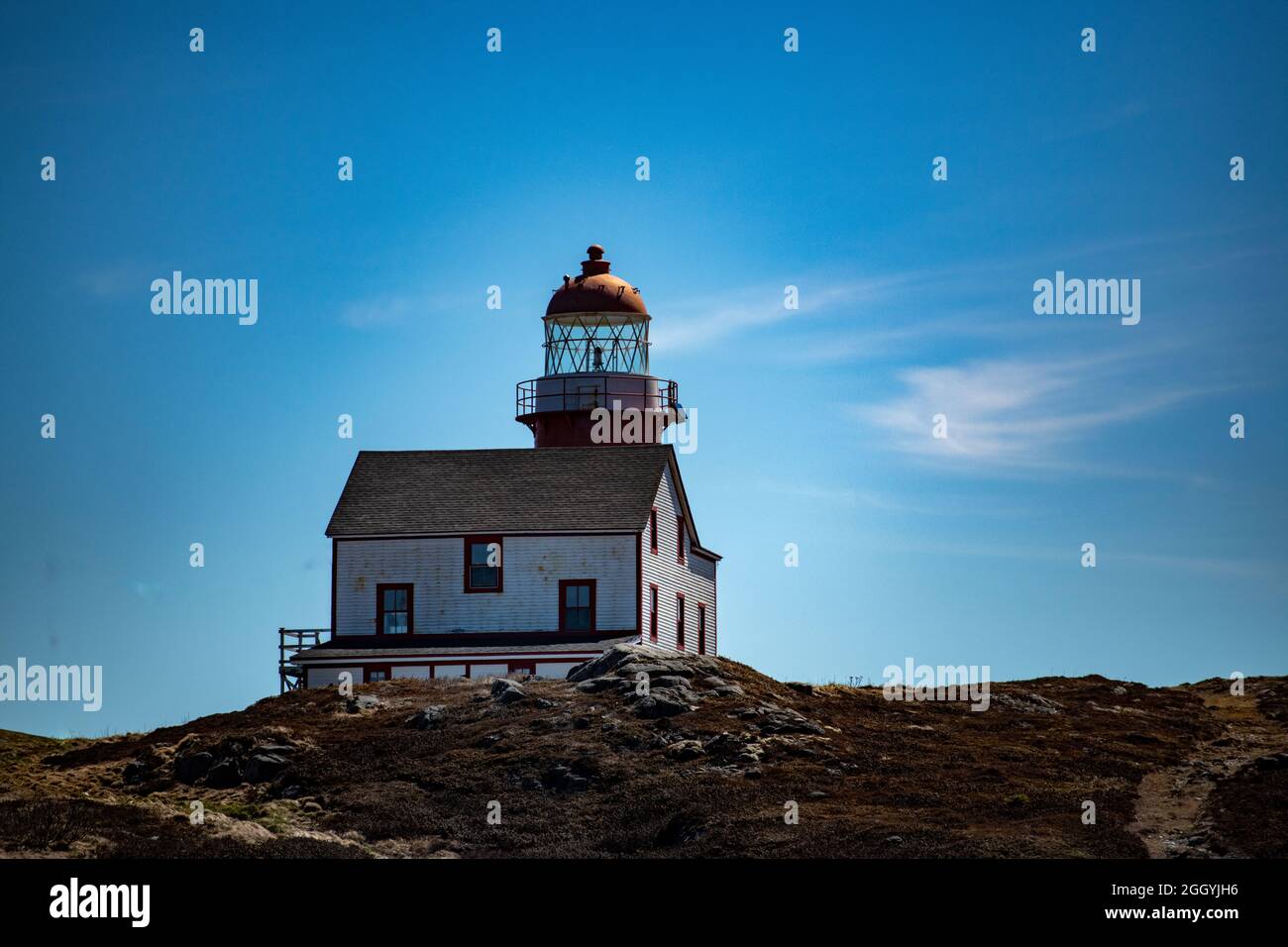 A vintage wood lighthouse and tower with a round red metal roof.  In the center of the lighthouse is a vintage lamp made of multiple pieces of glass. Stock Photo