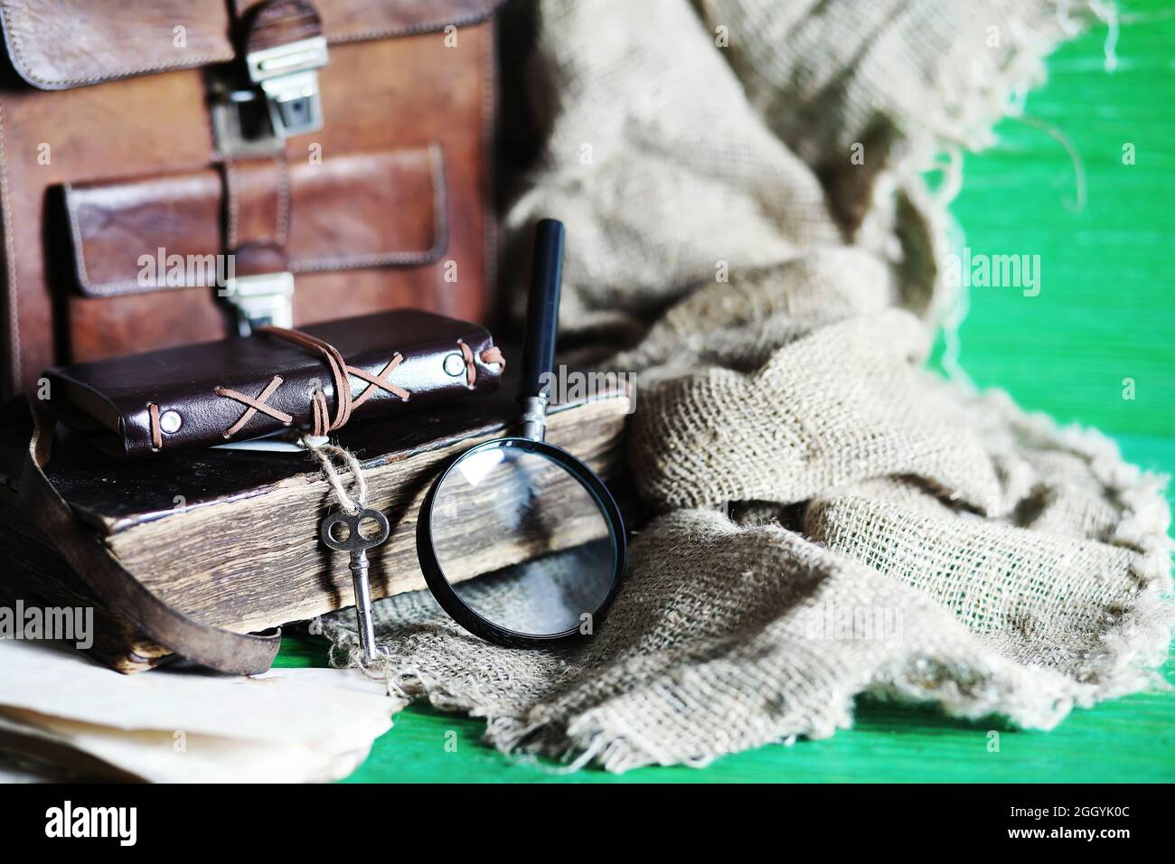 Old leather bag with a magnifying glass on a brown traveler wooden table background copy space. Stock Photo