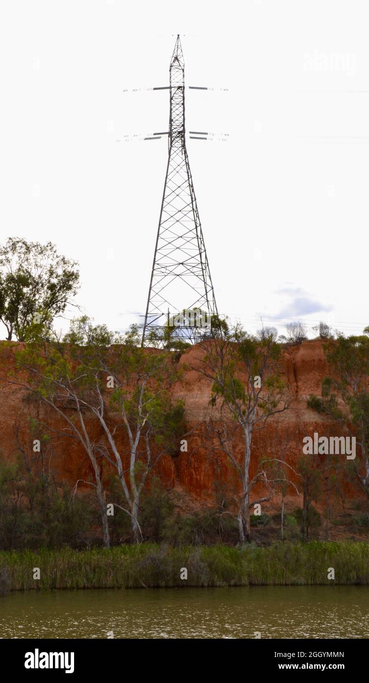 Electrical pylon with high tensile wires on top of red dirt cliff along the Murray River near Mildura Stock Photo