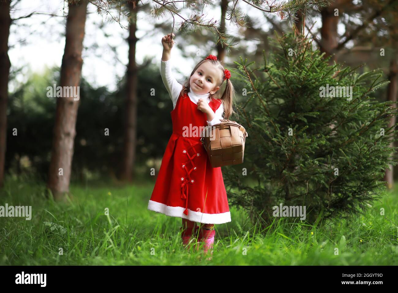 A little girl in a red hat and dresses is walking in the park. Cosplay ...