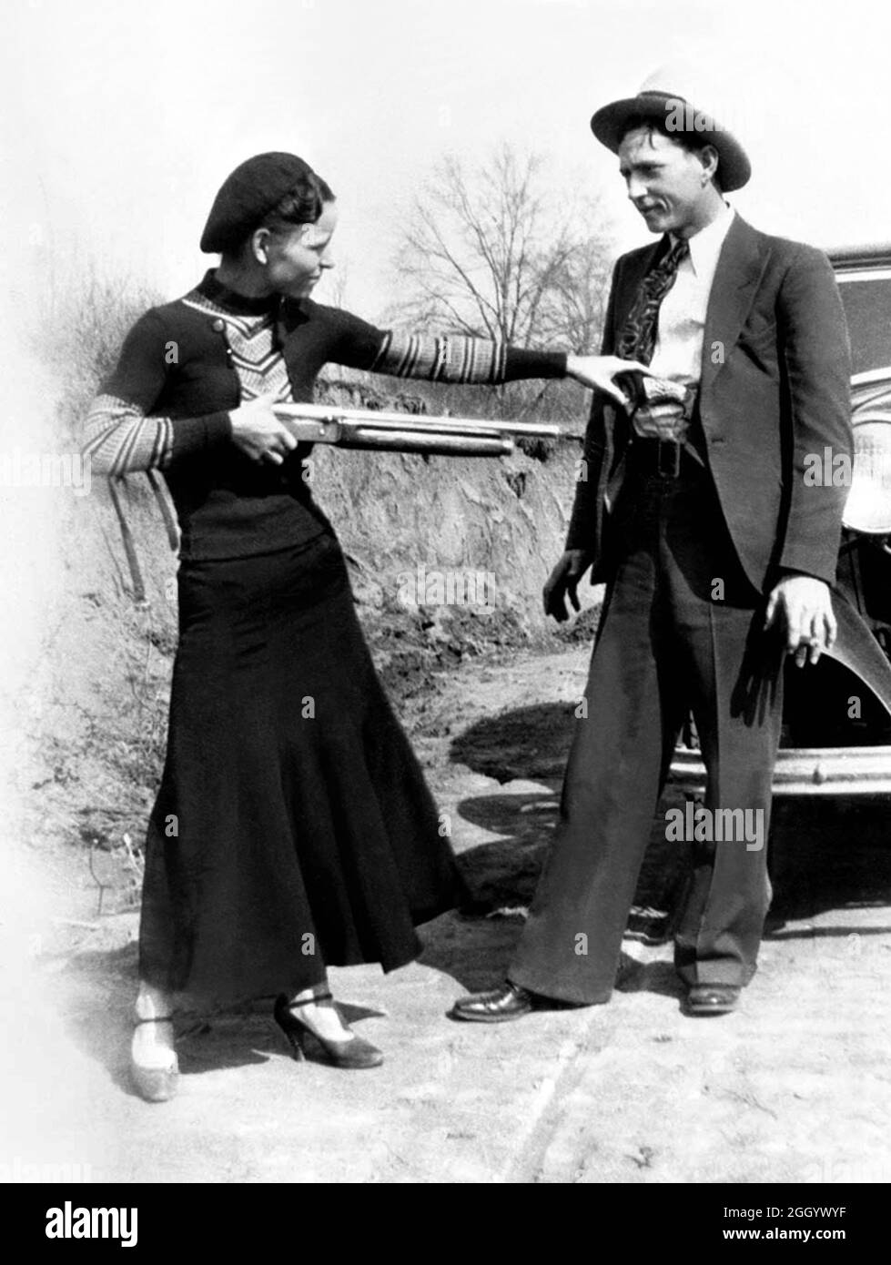 1934 , Arkansas , USA : The famous gangsterns  BONNIE PARKER  ( 1910 - 1934 ) and CLYDE BARROW ( 1909 - 1934 ). Contrary to popular belief the two never married. They were in a long standing relationship. Posing in front of a 1932 Ford V8 automobile. Recovered from Bonnie and Clyde after their deaths on May 23, 1934 . Unknown photographer . - OUTLAWS - KILLER - ASSASSINO - delinquente - criminalità organizzata  - GANGSTERN - Bos - CRONACA NERA - CRIMINALE - car - automobile - hat - cappello - fucile - arma - gun - rifle - shoes - scarpe ---  Archivio GBB Stock Photo