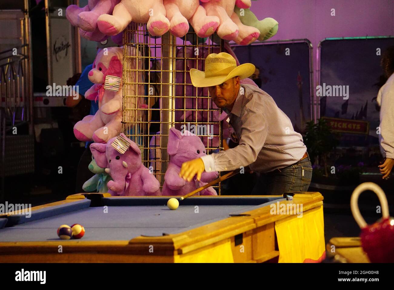 Cowboy playing pool at a fair game attraction on The Midway at the 2021 Minnesota State Fair, St. Paul, Minnesota. Stock Photo