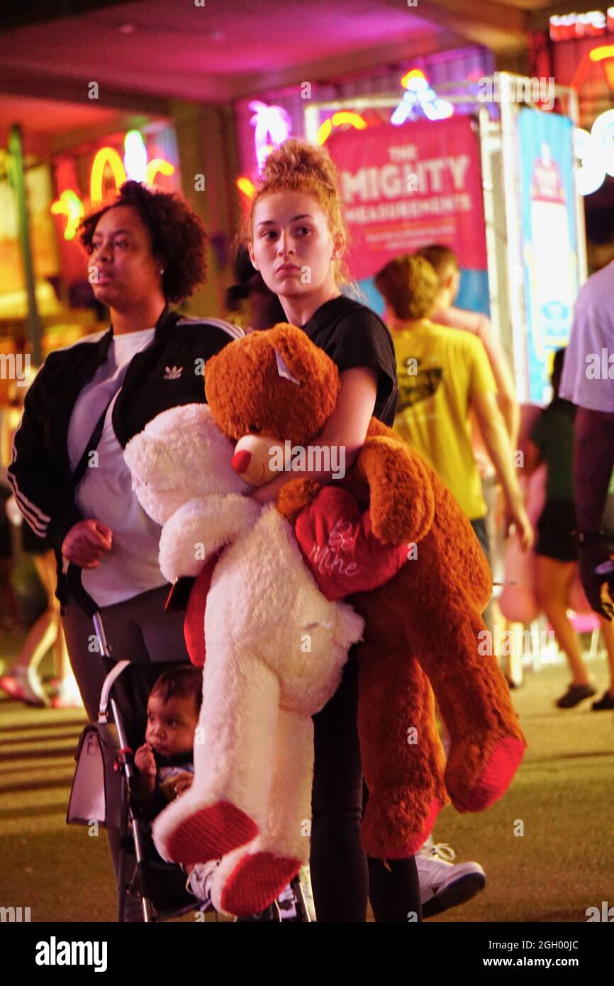 Woman holding giant stuff teddy bears on The Midway at the 2021 Minnesota State Fair, St. Paul, Minnesota. Stock Photo