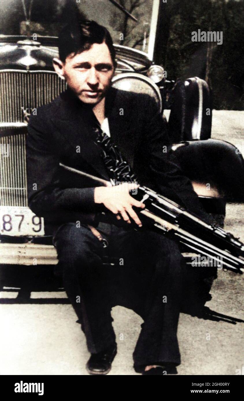 1934 , USA : Clyde Barrow with a gun . The famous gangsterns couple  BONNIE PARKER  ( 1910 - 1934 ) and CLYDE BARROW ( 1909 - 1934 ). Contrary to popular belief the two never married. They were in a long standing relationship. Posing in front of a 1932 Ford V8 automobile where Bonnie and Clyde dead on May 23, 1934 . Unknown photographer . DIGITALLY COLORIZED .- OUTLAWS - KILLER - ASSASSINO - delinquente - criminalità organizzata  - GANGSTERN - Bos - CRONACA NERA - CRIMINALE  ---  Archivio GBB Stock Photo