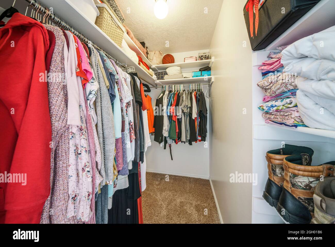 Narrow walk-in closet interior with clothes, shoes and bags Stock Photo