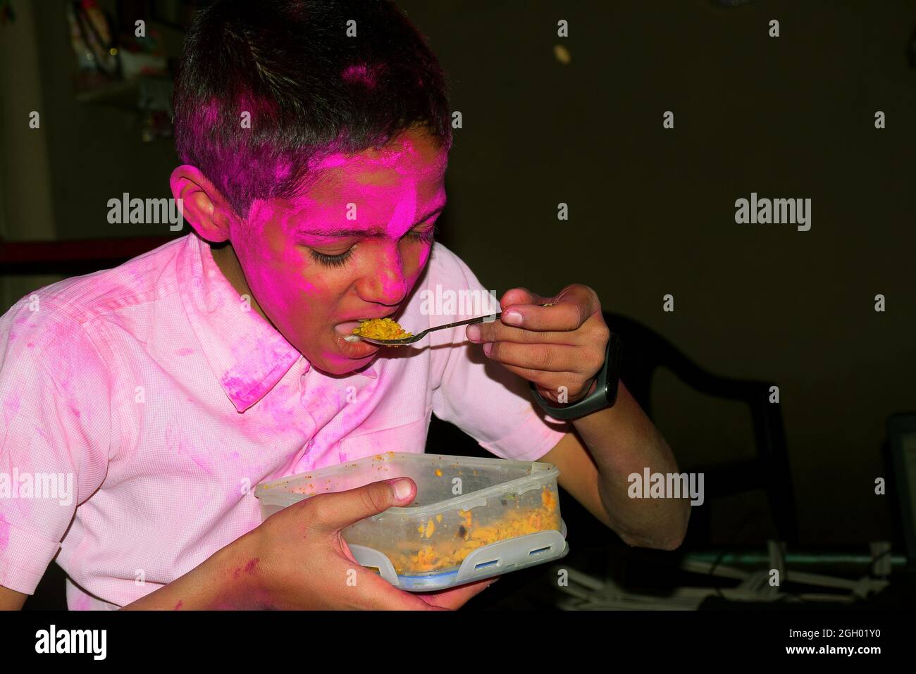 Boy with colorful face eating breakfast. Concept for Indian festival Holi Stock Photo
