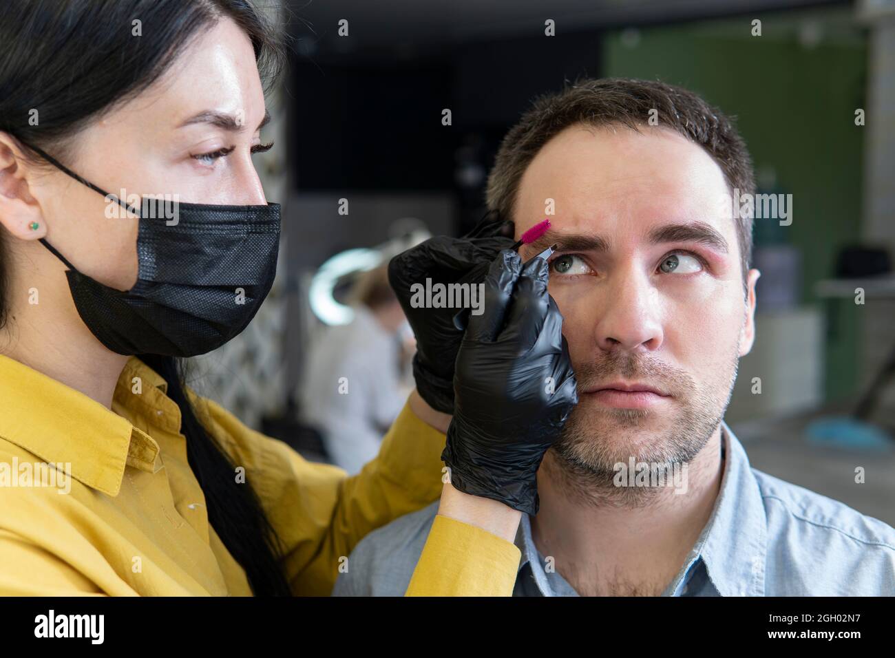 a young man on the procedure of eyebrow correction in a beauty salon