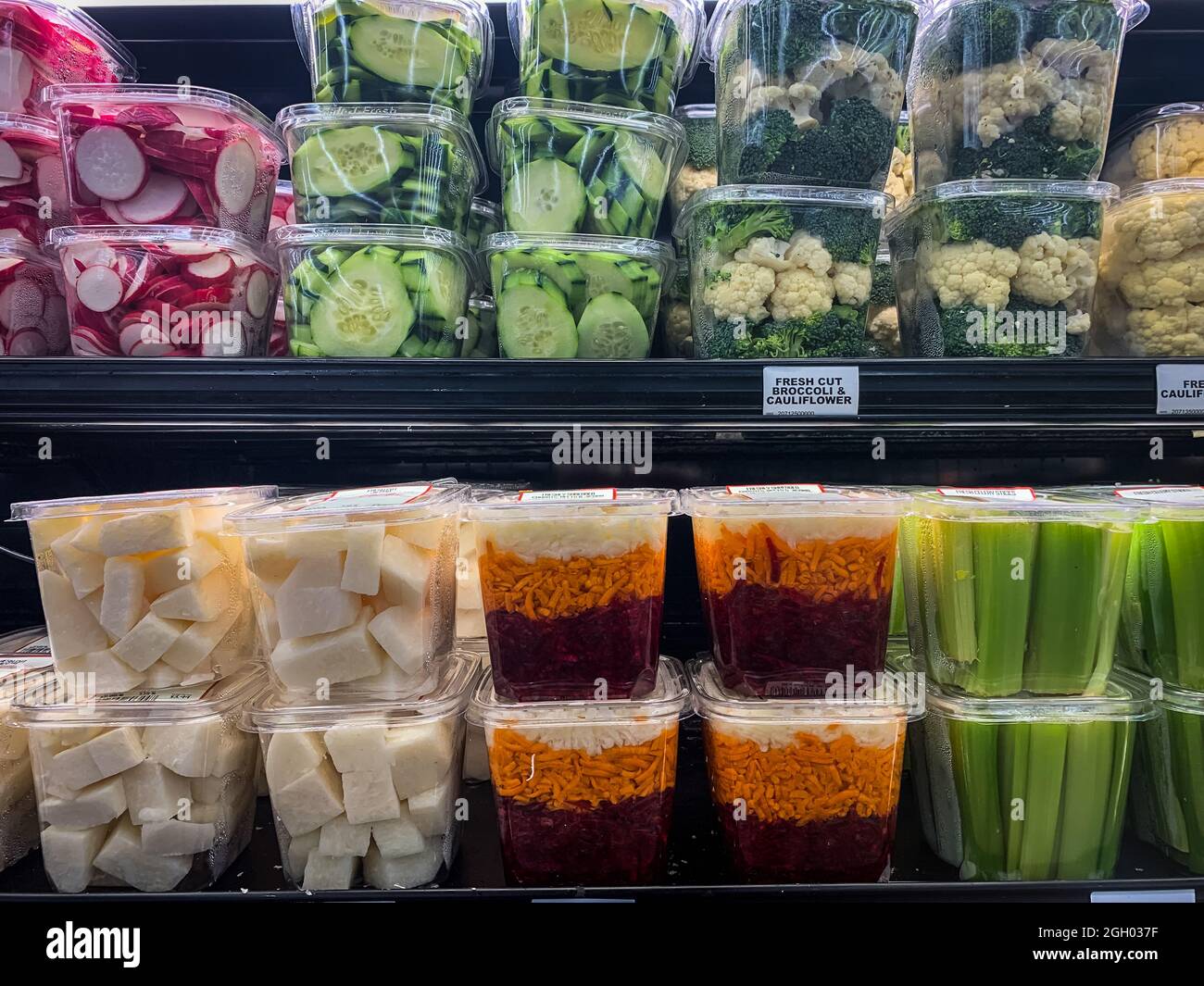 Freshly cut veggies in plastic containers arranged on shelves at grocery store Stock Photo