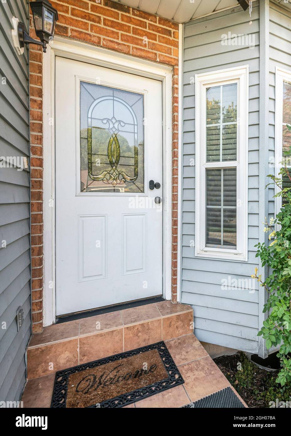 Vertical Front door exterior with bricks and vinyl siding wall Stock