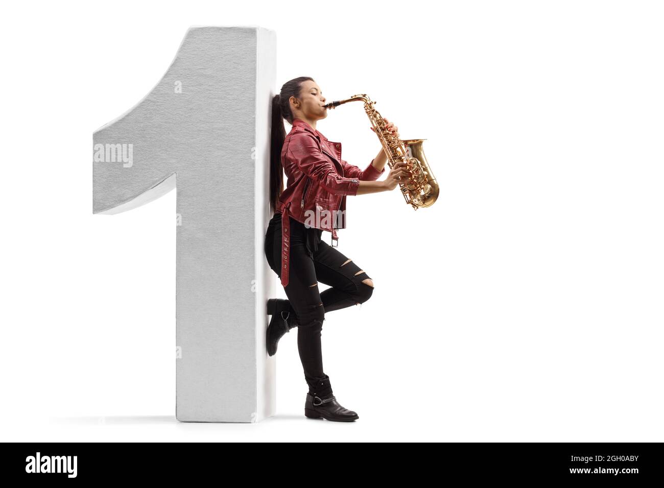 Full length profile shot of a female saxophonist playing and and leaning on a number one isolated on white background Stock Photo