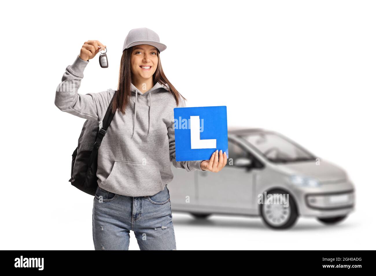 Female teen student holding a learner plate and a car key from a silver car isolated on white background Stock Photo