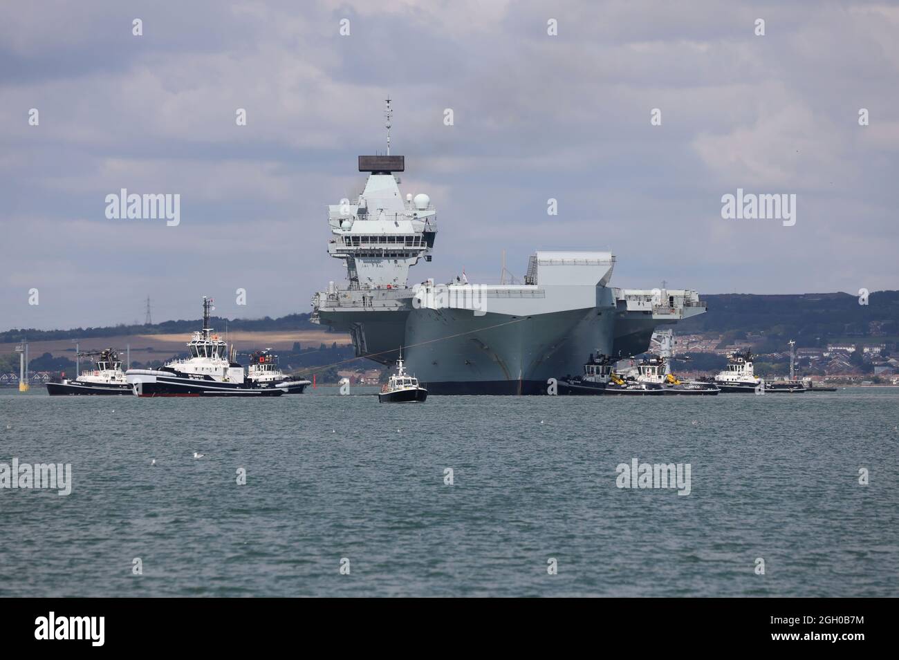 Tugs position the aircraft carrier HMS PRINCE OF WALES in the harbour. The ship departs for further sea trials Stock Photo