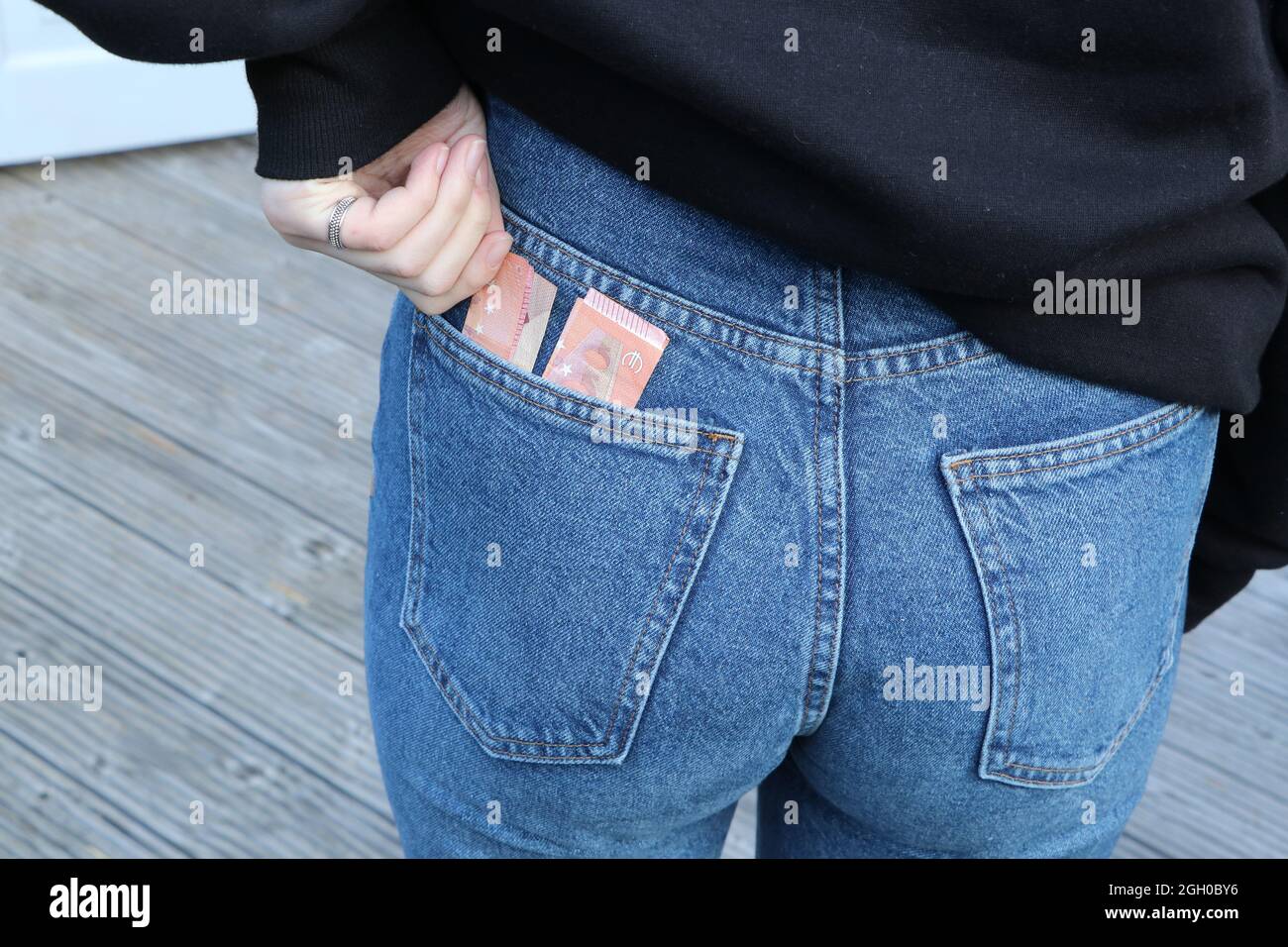 Pocket money, young adult with euro notes in back pocket of jeans Stock Photo