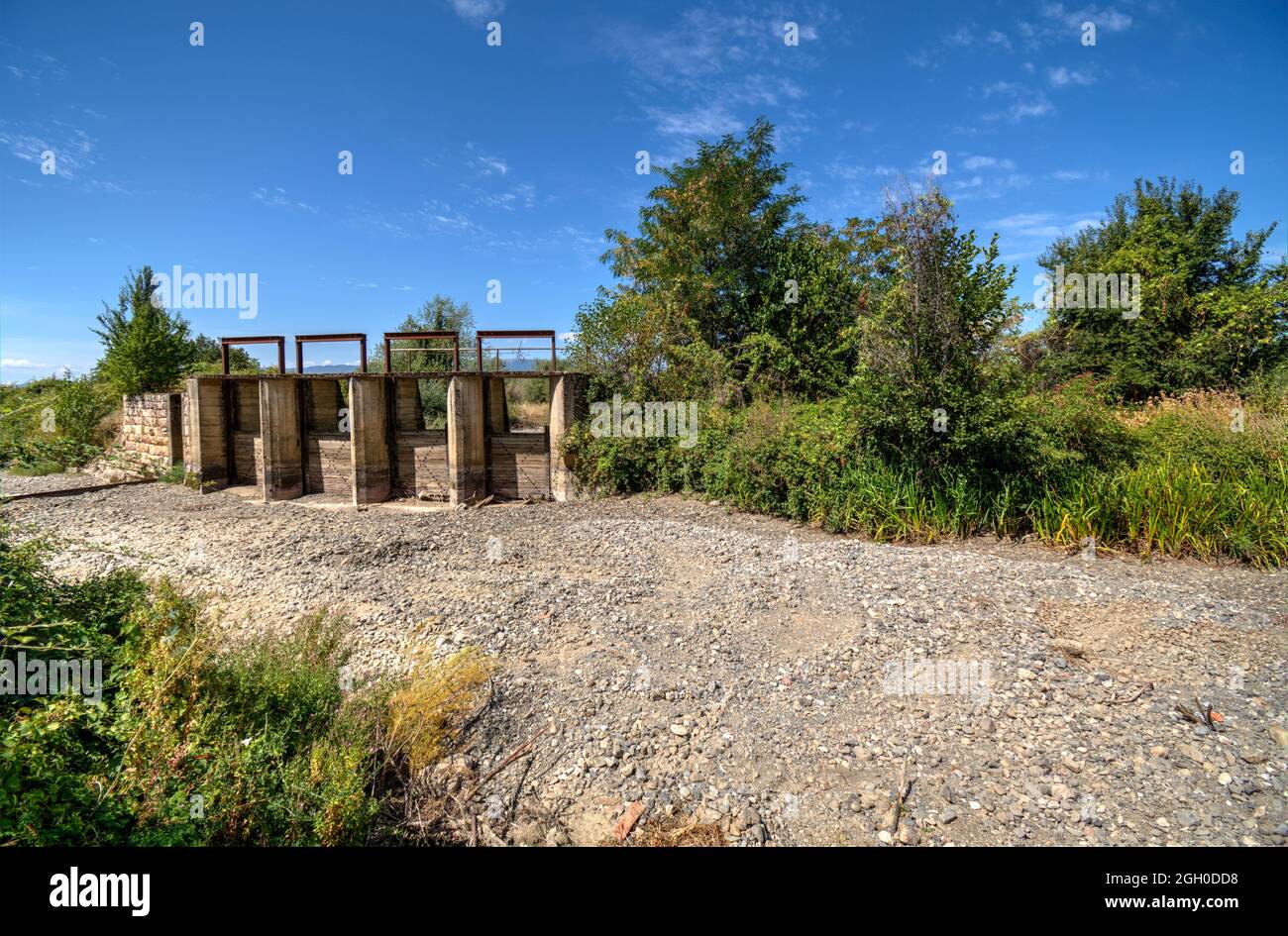 The riverbed without water, the drought takes its toll. The riverbedbed is paved with stones. Dam for regulation of the water. Stock Photo