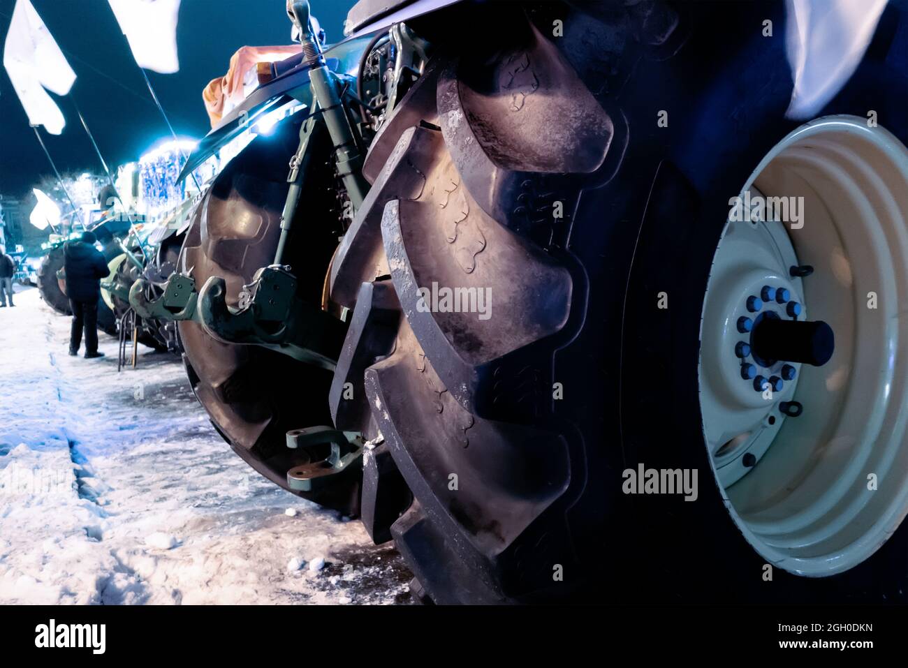 Tractors stand in a row on a winter street. View of rubber tires Stock