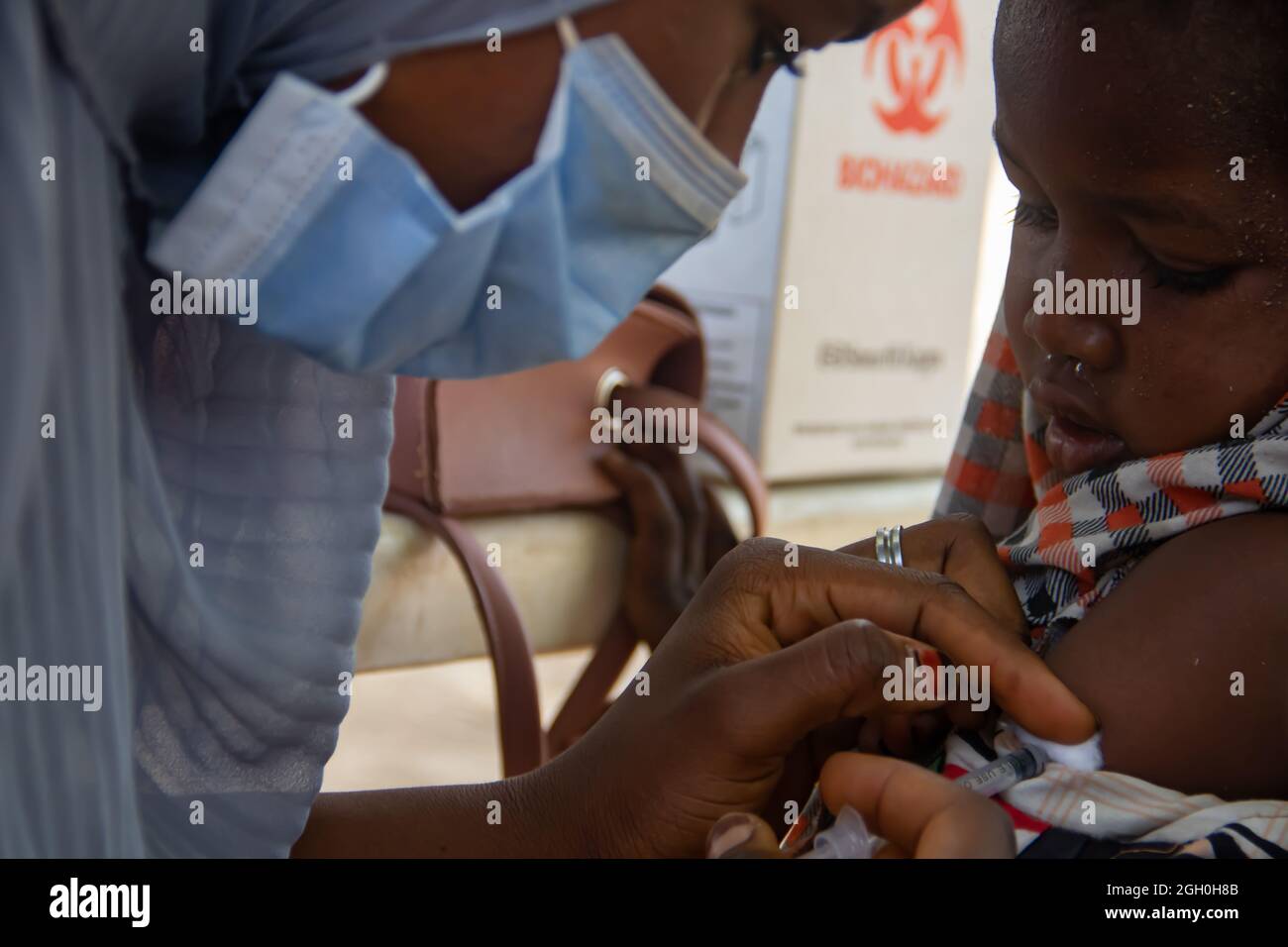 Medical worker doing routine immunization vaccination in refugee camp in Africa Stock Photo