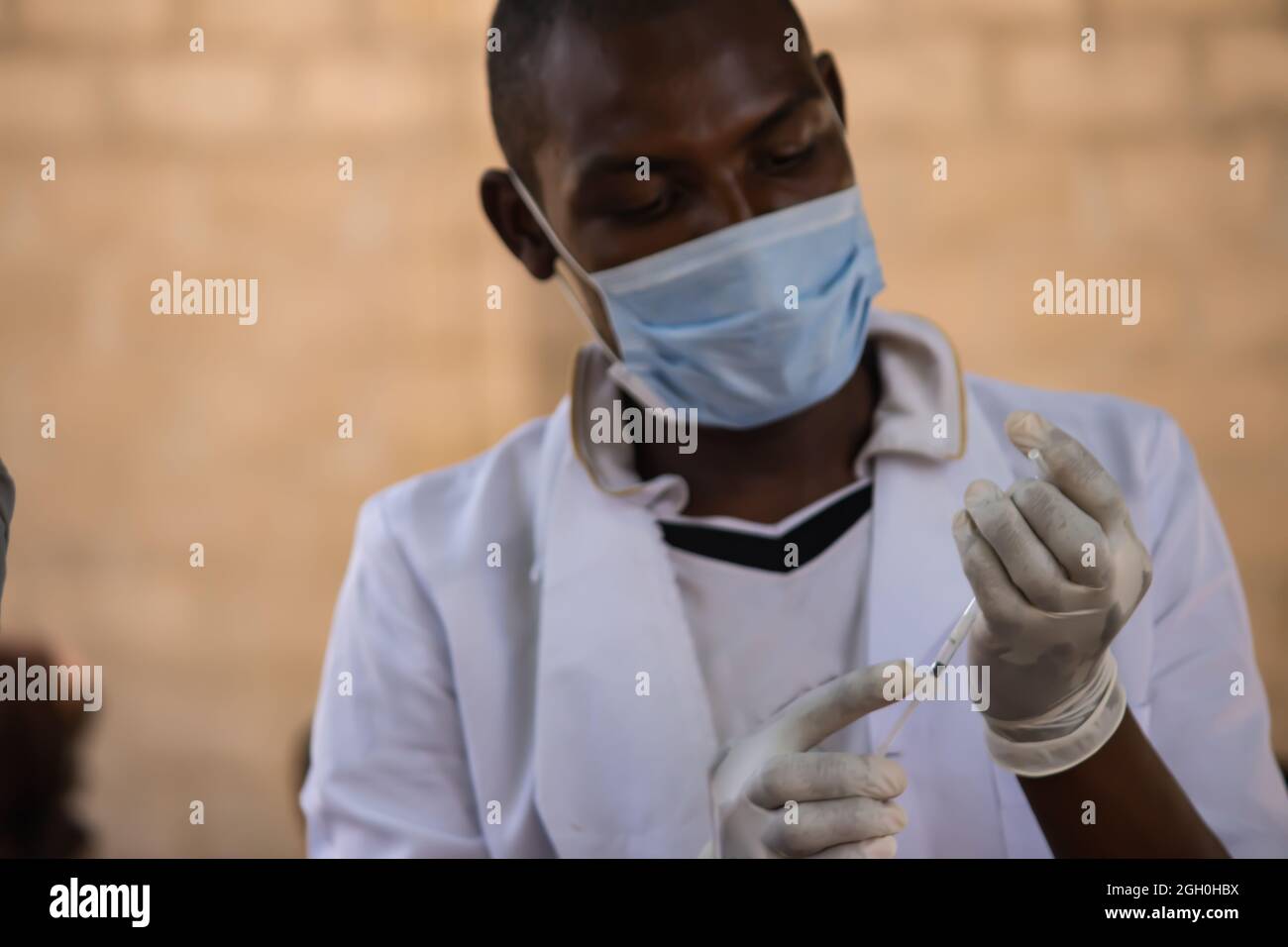 Medical worker preparing vaccine for routine immunization vaccination for children under 9 years, in refugee camp in Africa Stock Photo