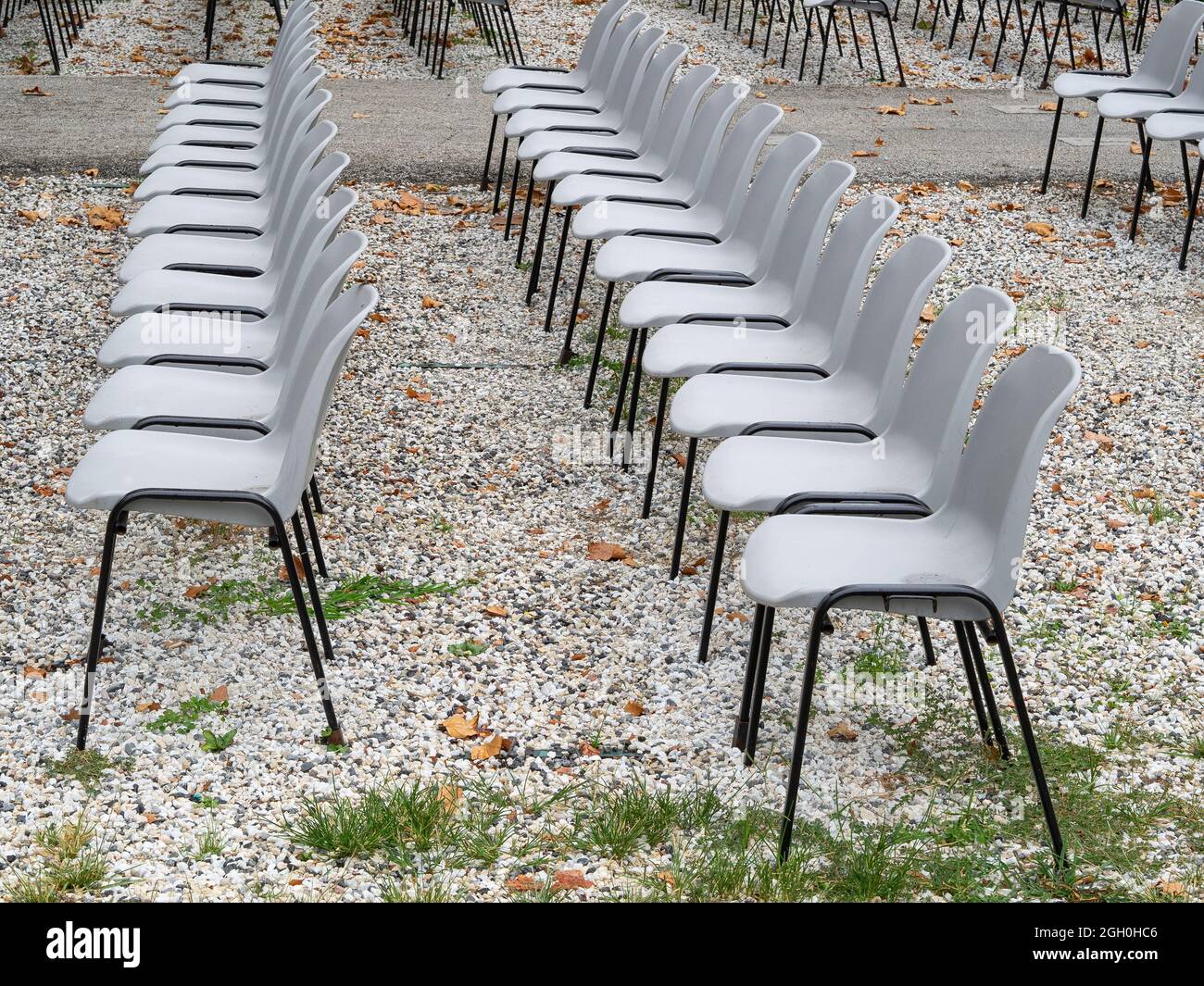 group of empty grey plastic chair arranged in rows waiting for the people after coronavirus covid 19 pandemic Stock Photo