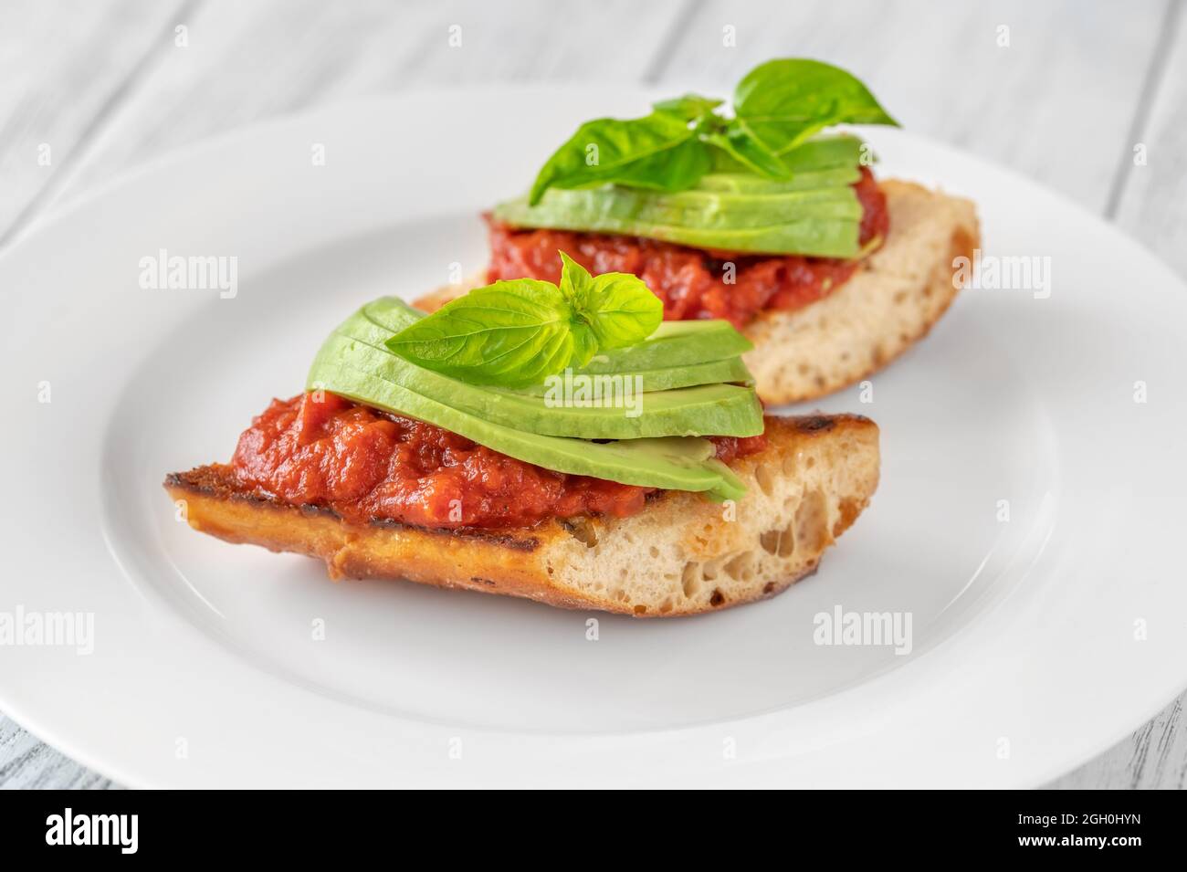 Bruschettas with tomato spread and slices of avocado Stock Photo