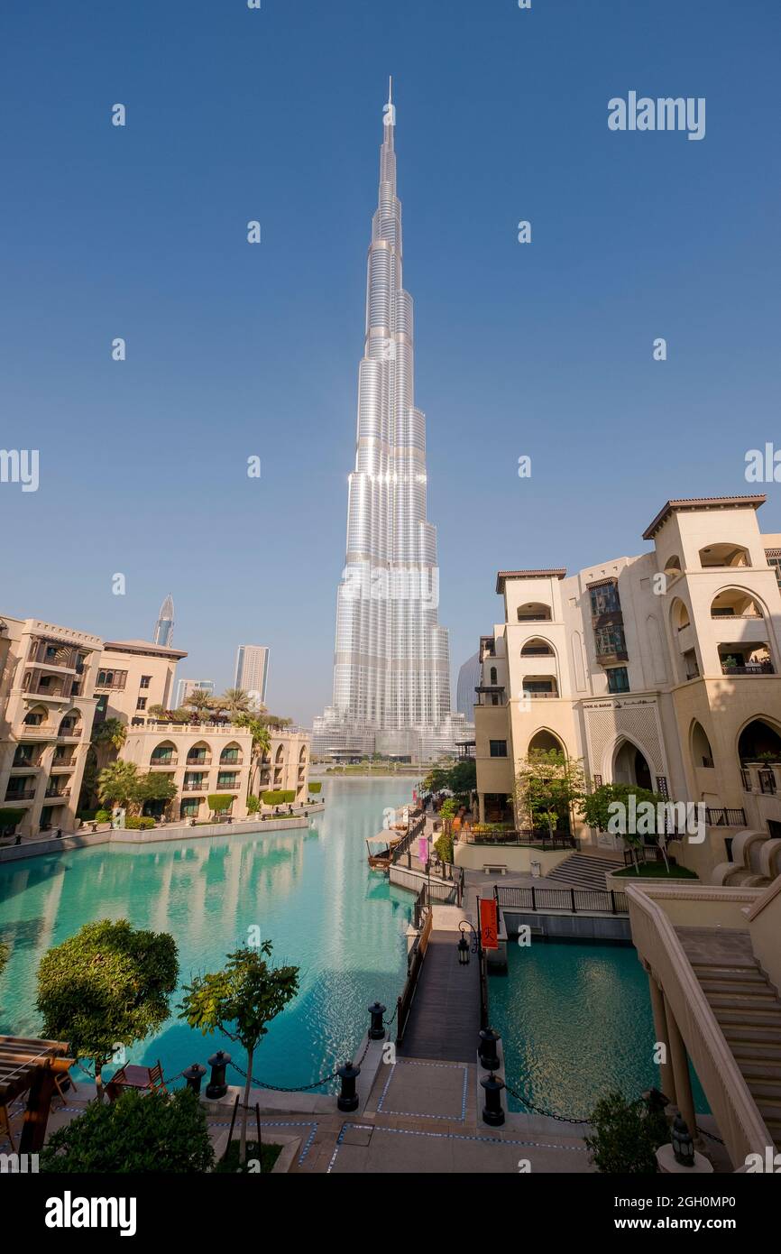 The skyscraper Burj Khalifa in the background of new mixed development, pedestrian bridge and lake. In Dubai, United Arab Emirates. Stock Photo