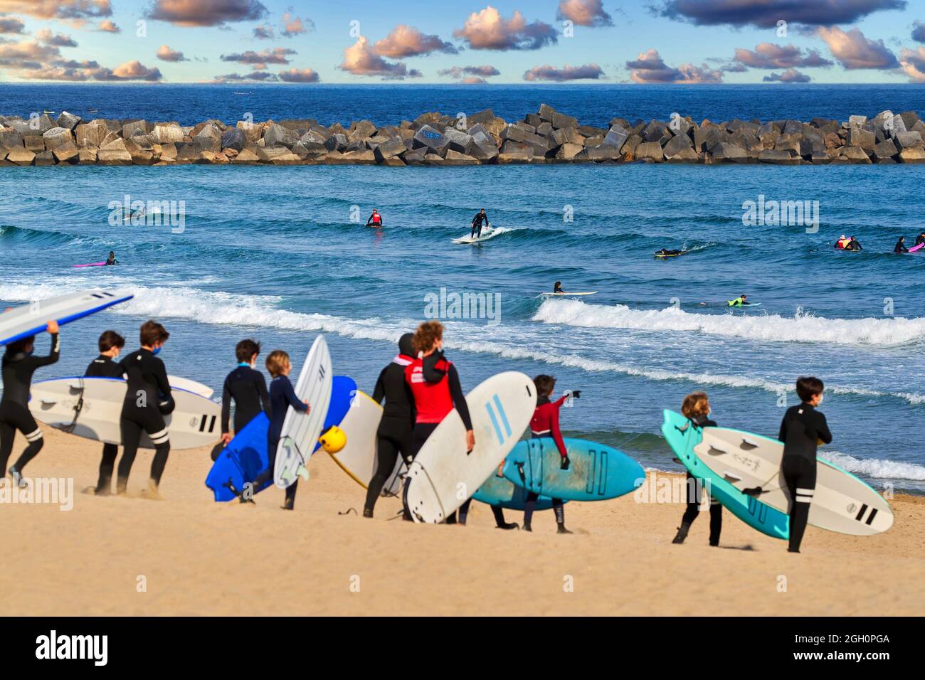 Group of young people take a surf lesson on La Zurriola beach, Donostia, San Sebastian, Basque Country, Spain, Europe. La Zurriola is the Stock Photo