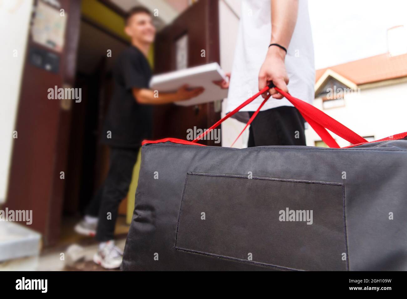 food delivery, mail and people concept - man delivering pizza in thermo bag to customer home and gave it to a customer Stock Photo