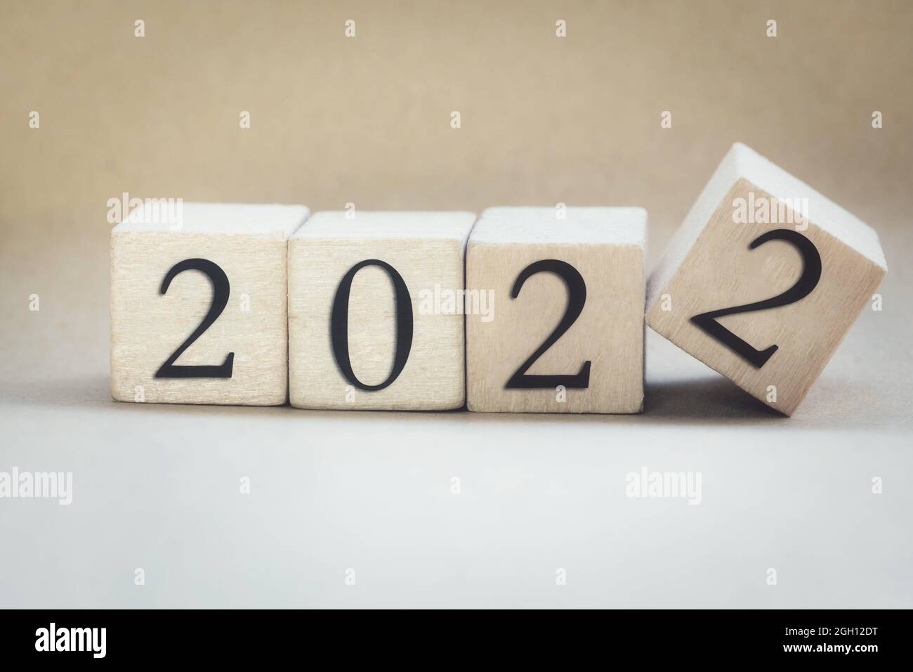 The year 2022 written on wooden cubes, finger flipping year to year, New year concept background, starting new natural modern colored design stylish Stock Photo