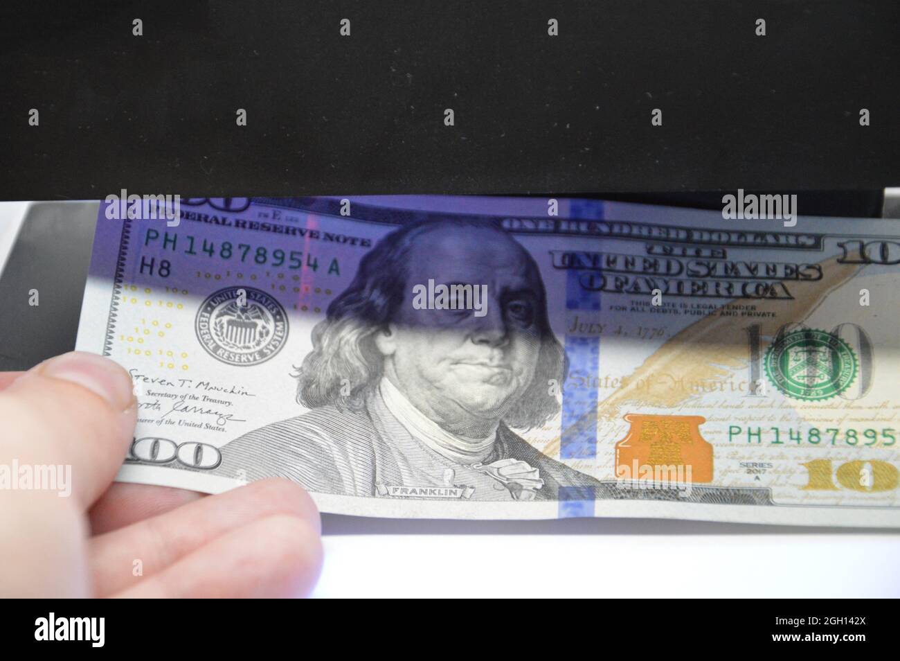 US dollars are checked for a authenticity. Stock Photo