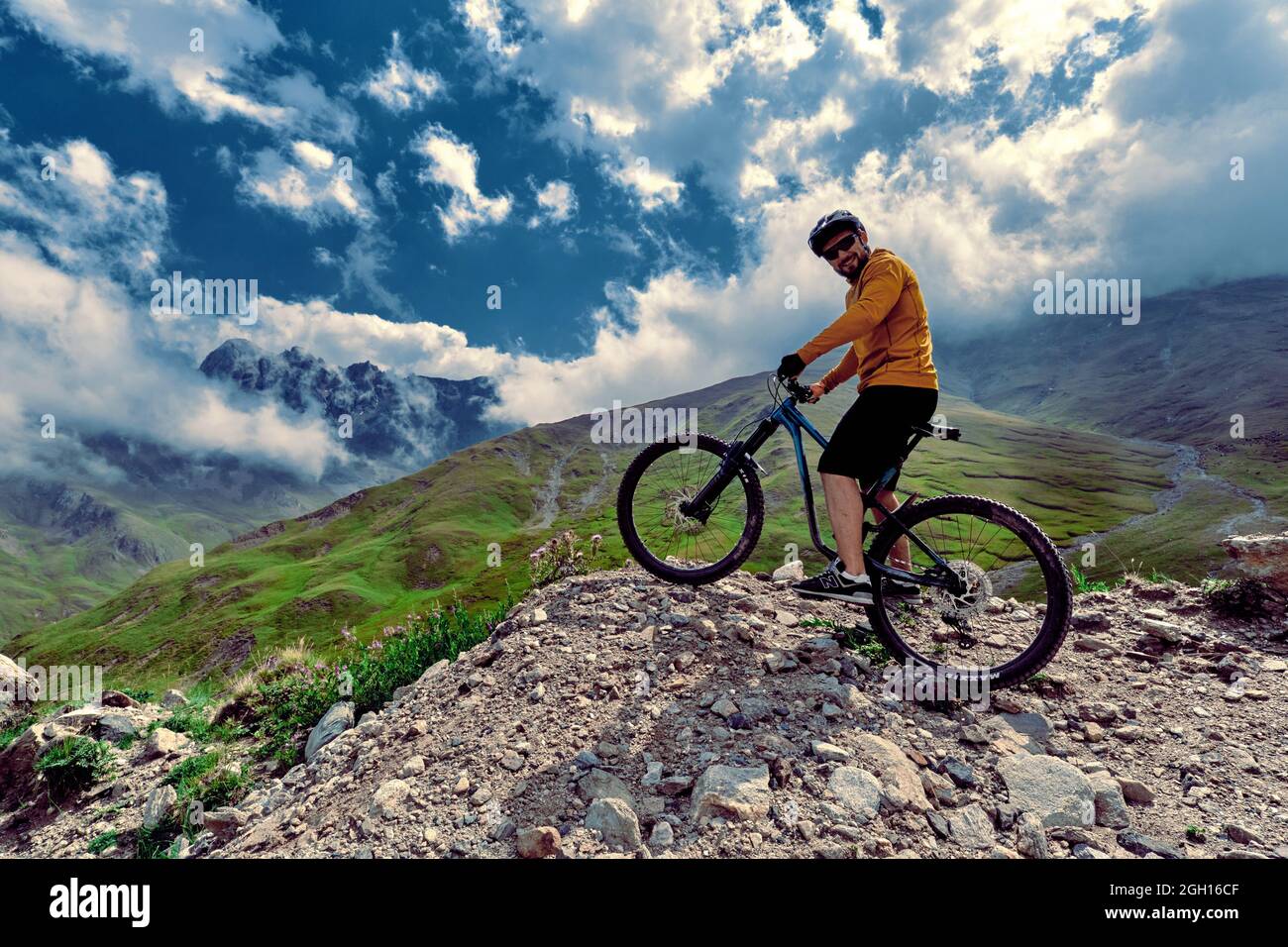 Elbrus, Kabardino-Balkaria, Russia - August 2017: Mountain biking in Elbrus. Cyclist on the top of a hill and enjoying view of the mountains. MTB bicy Stock Photo