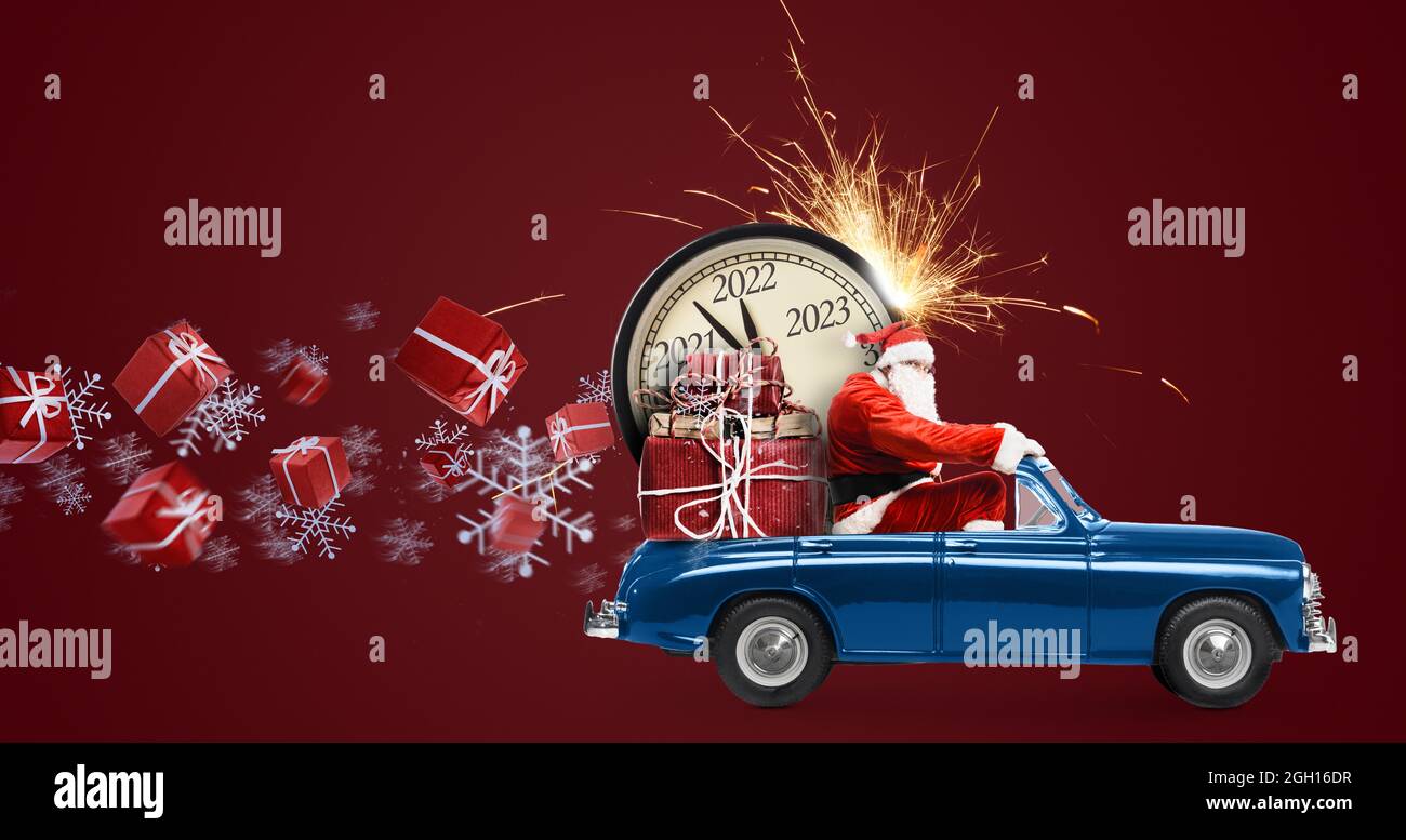 Christmas is coming. Santa Claus on toy car delivering New Year 2022 gifts and countdown clock at red background with fireworks Stock Photo