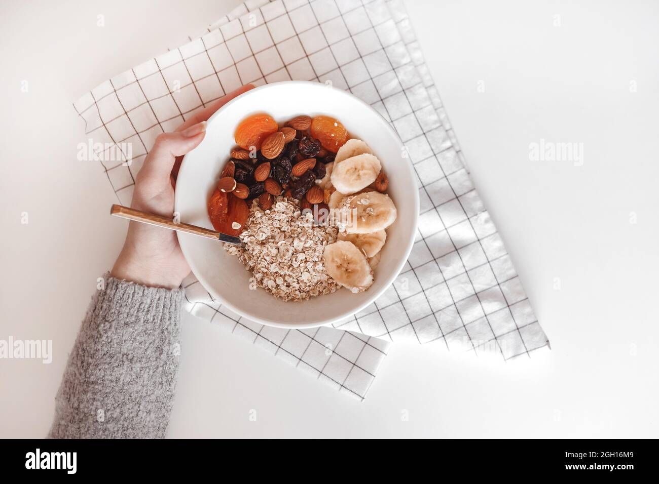 Carbohydrate healthy breakfast. Oatmeal with dried fruits on a white plate. View from above. Stock Photo