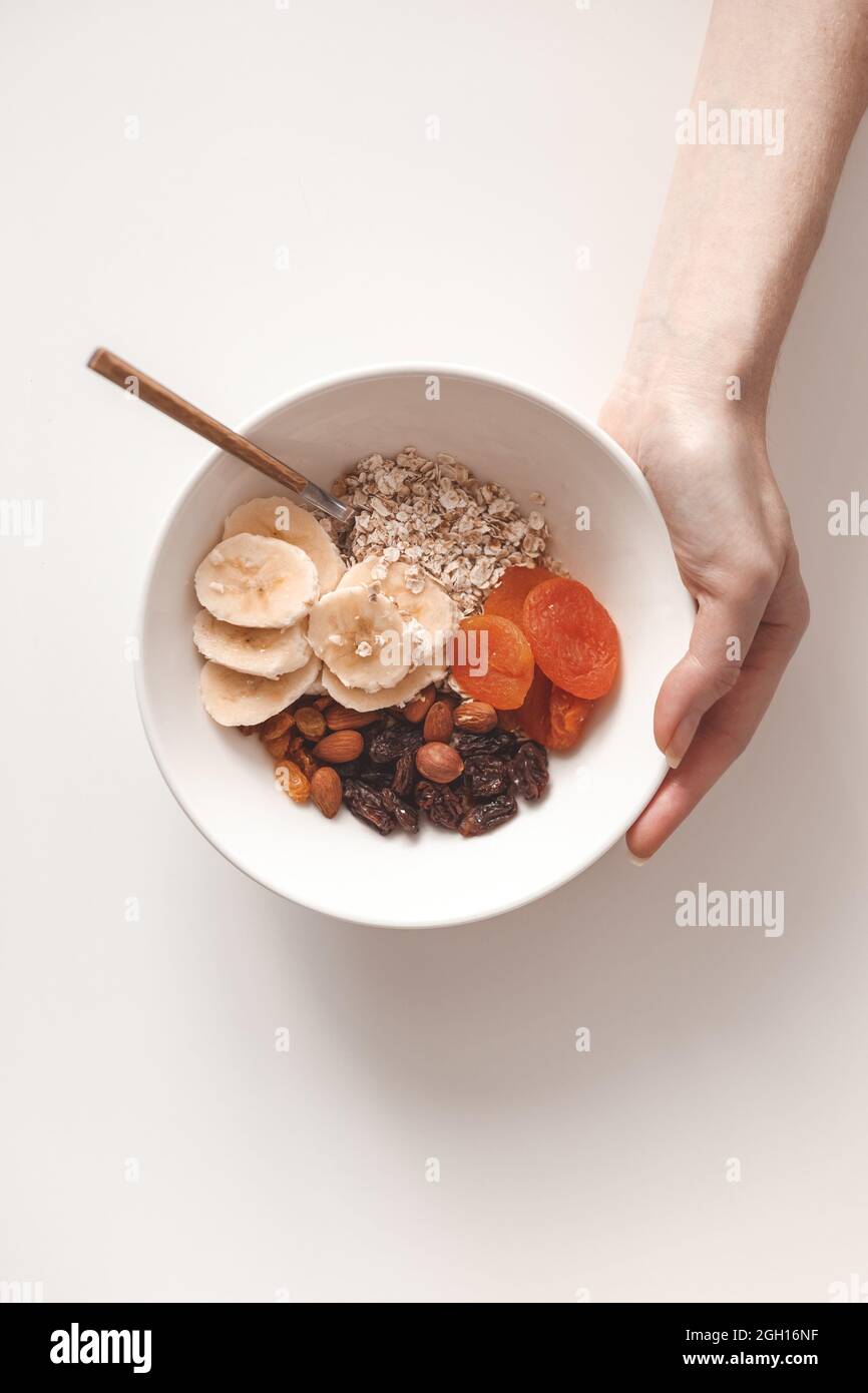 Carbohydrate healthy breakfast. Oatmeal with dried fruits on a white plate. View from above. Stock Photo
