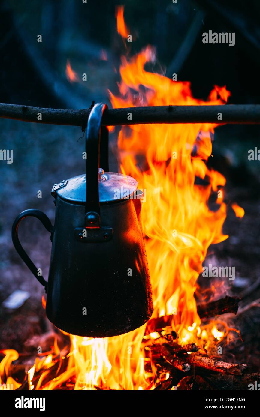 https://c8.alamy.com/comp/2GH17NG/old-retro-iron-camp-kettle-boils-water-on-a-fire-in-forest-bright-flame-fire-bonfire-at-dusk-night-2GH17NG.jpg