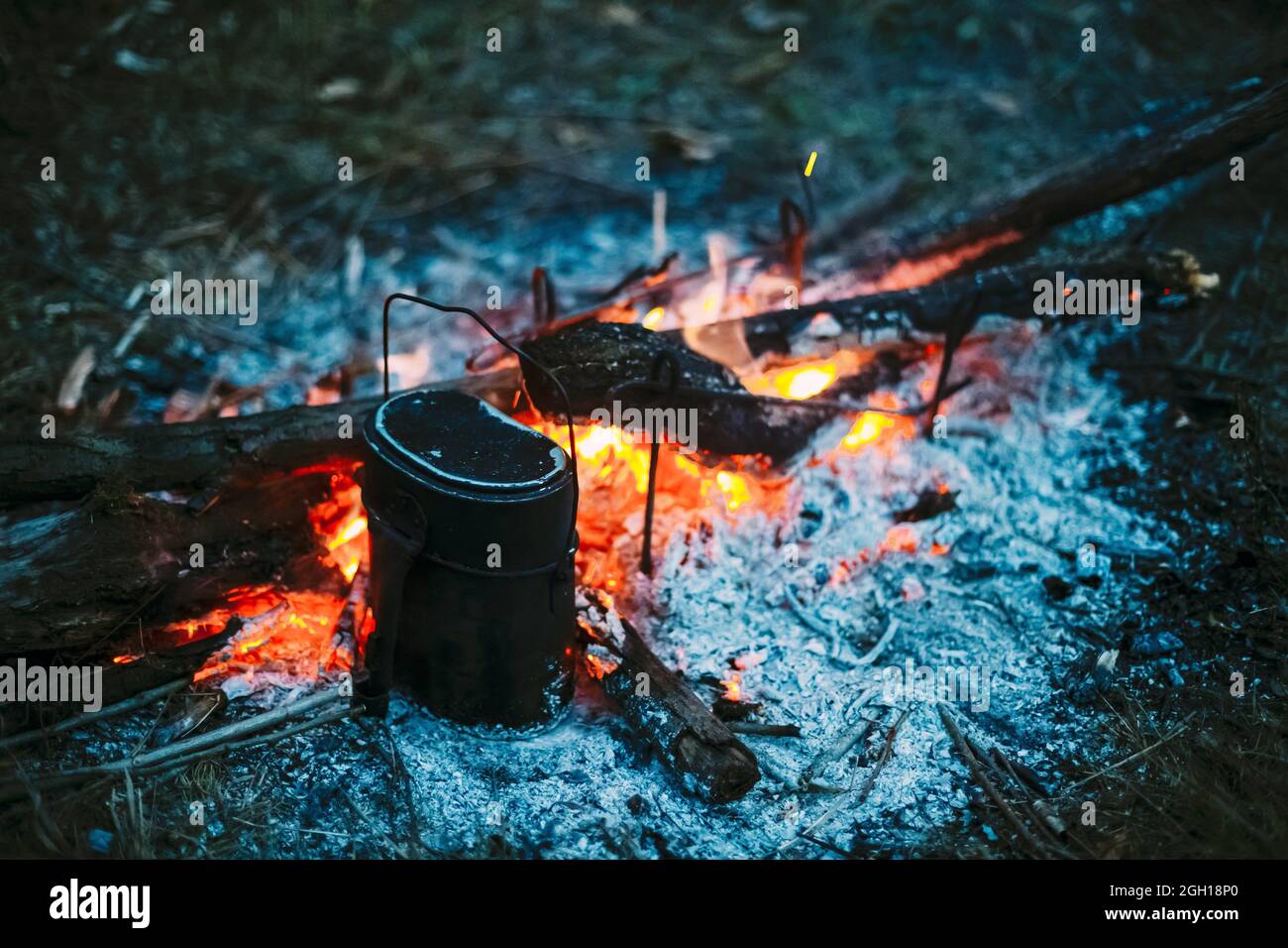 Food Is Cooked Over A Fire In An Old Vintage Retro Marching Pot Dixie. German Wehrmacht Infantry Soldier's Military Equipment Of World War II. Stock Photo