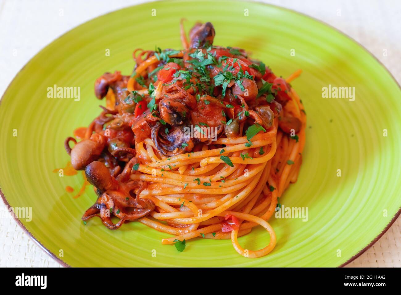 Spaghetti with octopus, tomato sauce, olives and capers. Typical recipe of Neapolitan cuisine, in Italy. Ready to eat. Stock Photo