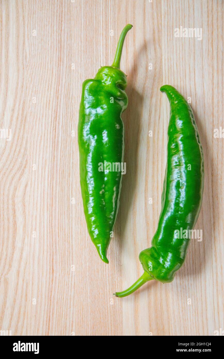 Two green peppers on wooden surface. Stock Photo