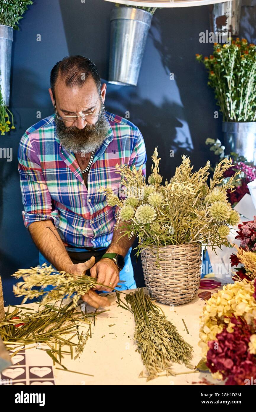 A florist taking care of various flowers and bouquets in his shop Stock