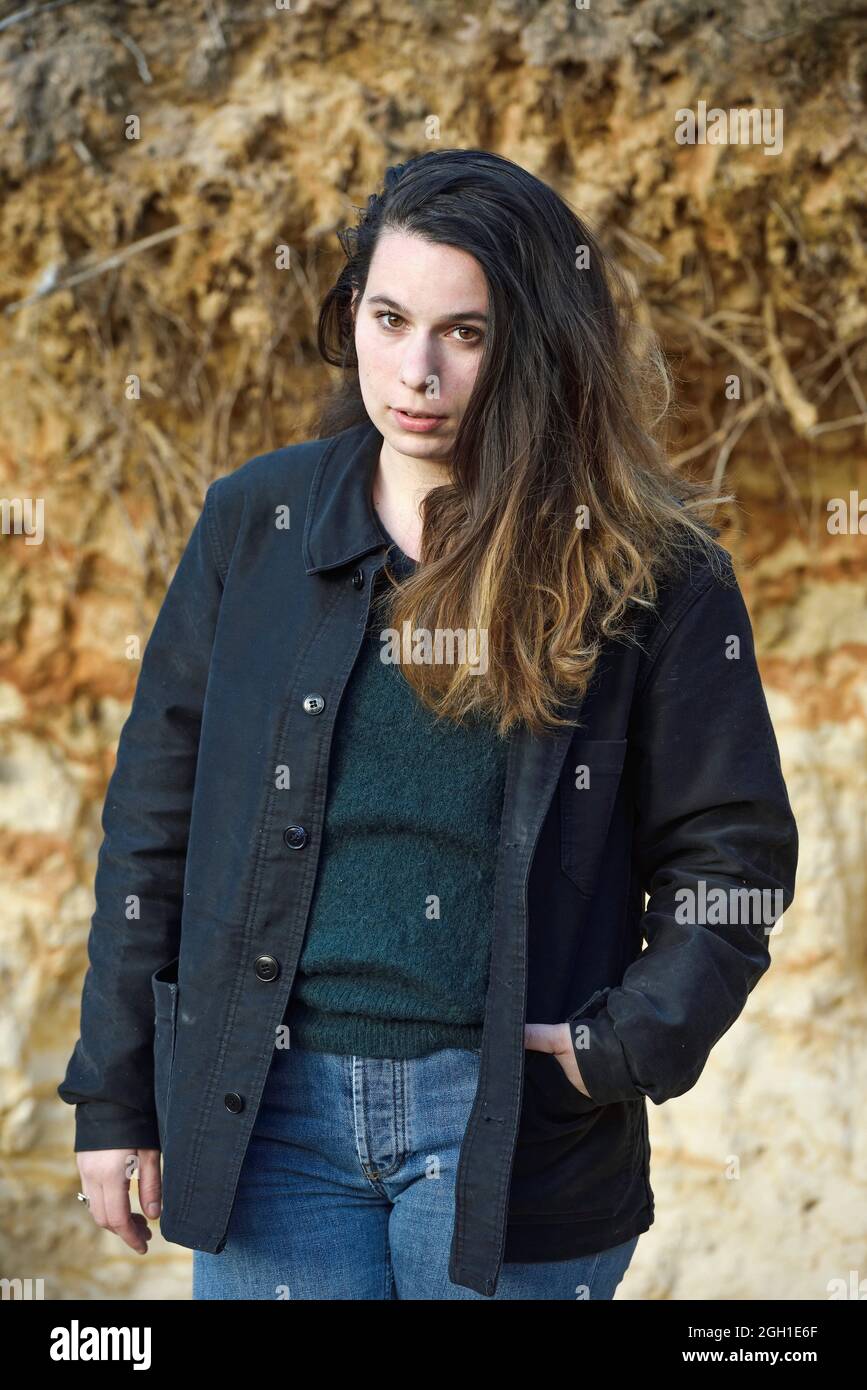 Portrait of a young woman, free hair, wearing a pull-over, a jacket and  jeans pants, France Stock Photo - Alamy