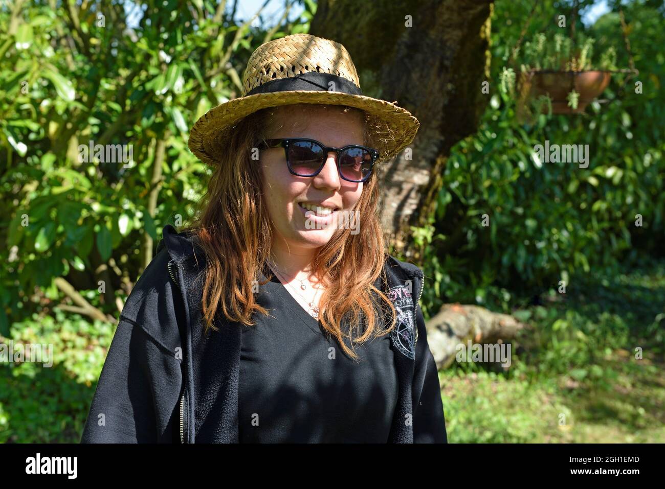 Portrait de jeune femme portant des lunettes de soleil et un chapeau de paille, Foret de Rambouillet, Parc naturel regional de la Haute Vallee de Stock Photo