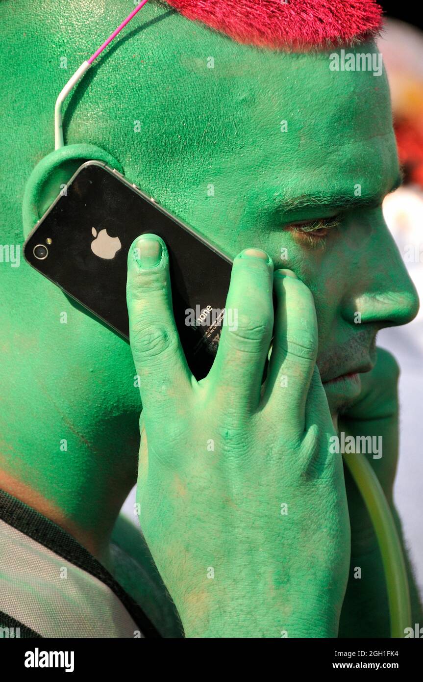 Portrait of young man, face painted in green color, hair painted in red color, talking by mobile phone, Lake Parade - LGBT Parade, Pride Parade, Stock Photo