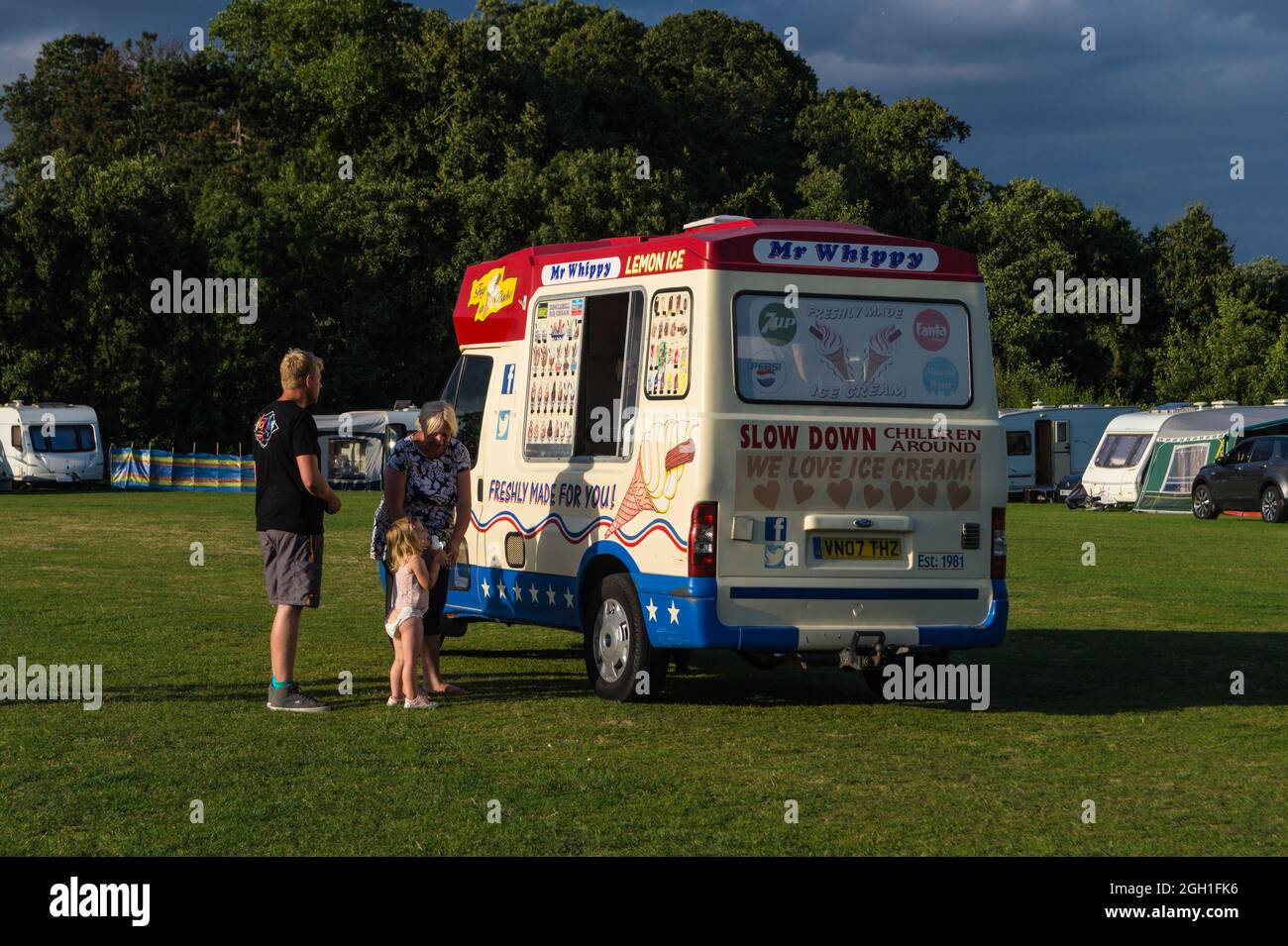 A young girl with adults at a 'Mr. Whippy' ice cream van, Applefields campsite, Leiston, Suffolk, England Stock Photo