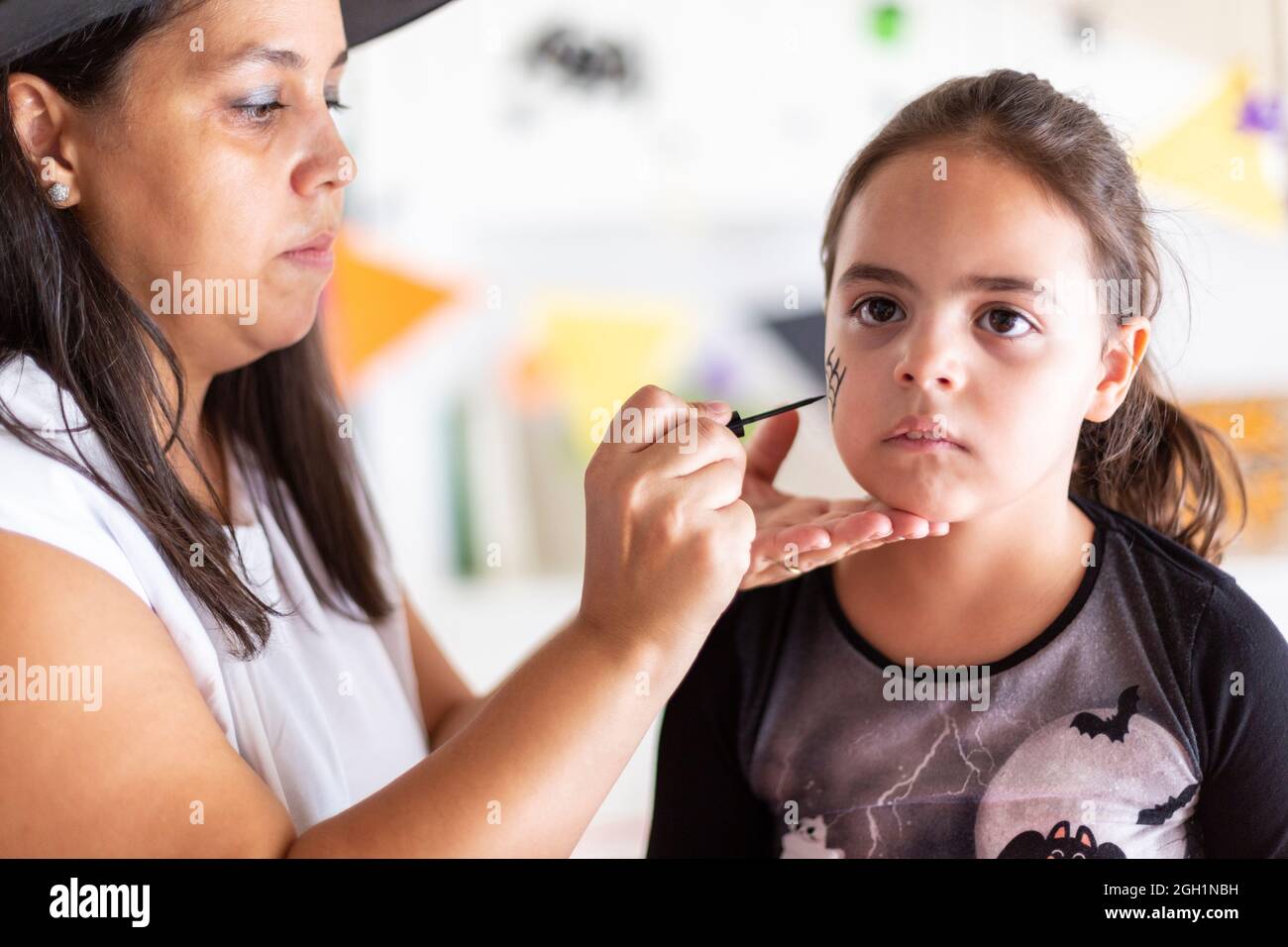 Close up of young caucasian woman making up little child for Halloween celebration. Stock Photo