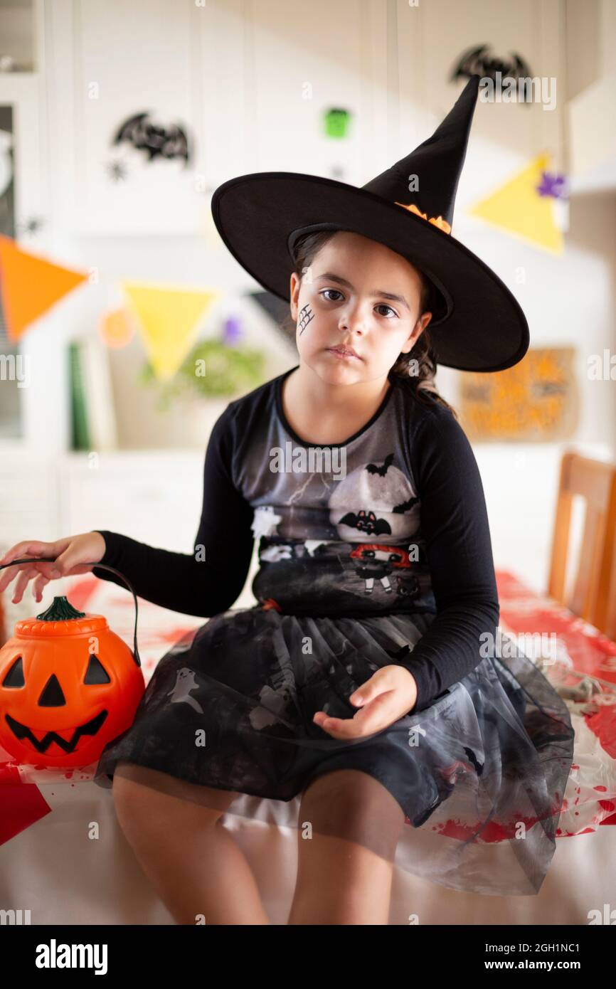 Portrait of little caucasian girl in witch costume with a pumpkin in ...