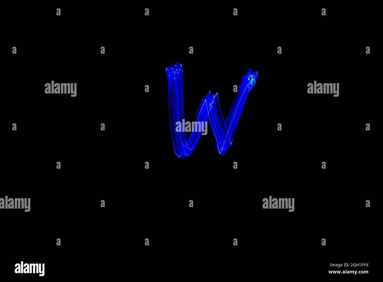 Letter W. Light painting alphabet. Long exposure photography. Drawn letter W with blue lights against black background. Stock Photo