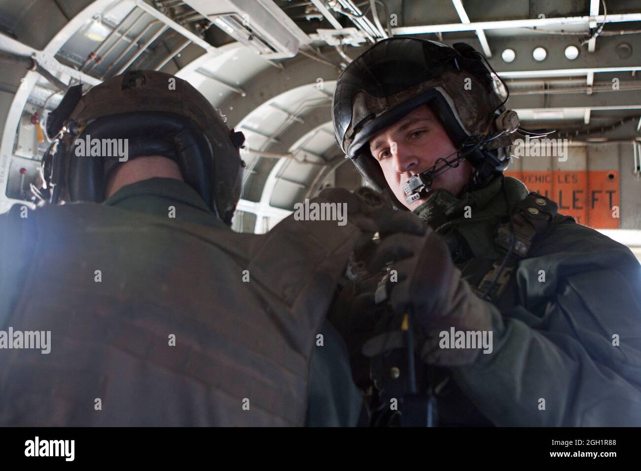 U.S. Marine Corps Lance Cpl. Madison DeLoach (right), aids Cpl. Zachary Hughes secure a plate carrier, Marine Heavy Helicopter Squadron 363, Camp Bastion, Helmand province, Afghanistan, Jan. 5, 2011. HMH-363 conducted flight operations in support of troops throughout the Helmand province. Stock Photo