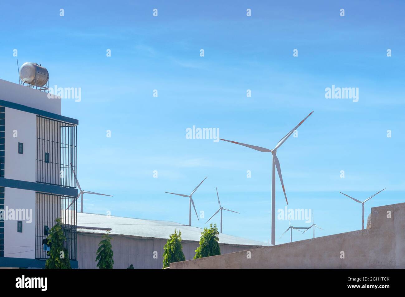 Wind power station among city building area. Renewable energy resource concept Stock Photo
