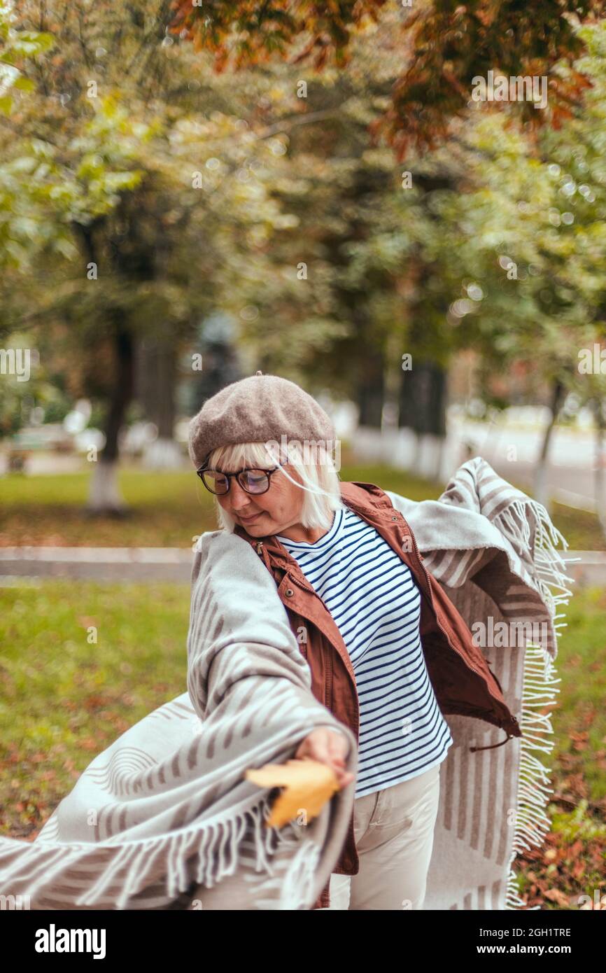 Caucasian senior woman in warm casual clothes and a cozy scarf having fun outdoors enjoying nature Stock Photo