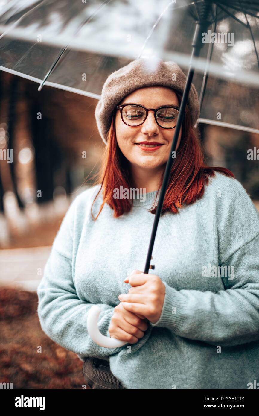 Young happy cheerful girl under transparent umbrella in autumn park Stock Photo