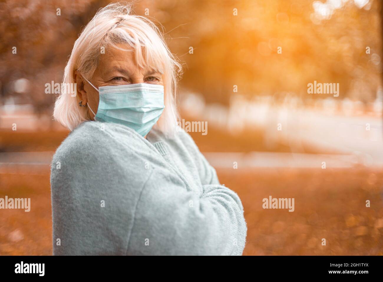 Coronavirus, COVID-19 Pandemic concept. Blonde woman in wearing face mask protective for disease virus SARS-CoV-2 at the city street Stock Photo