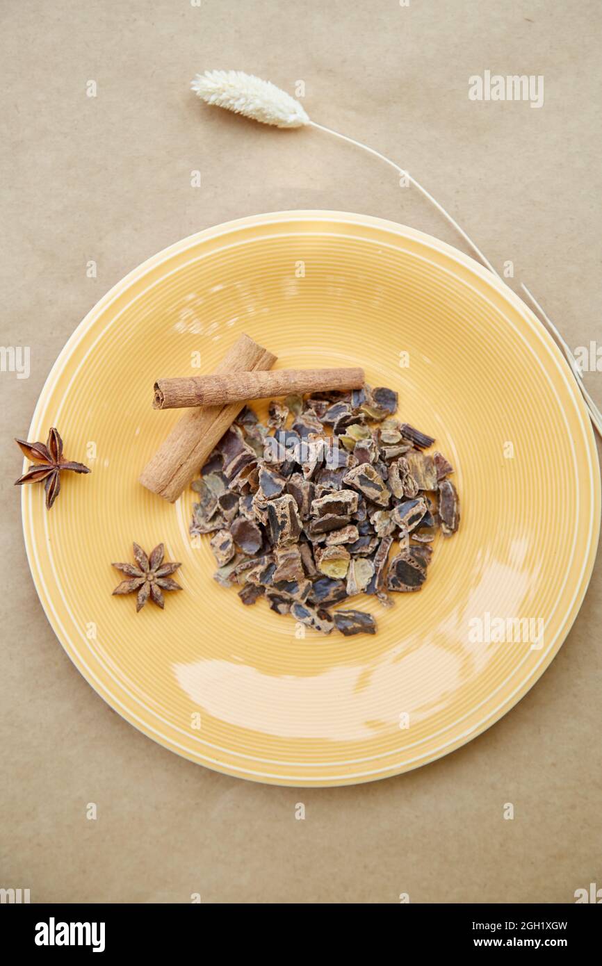 Plant-based alternative - natural carob. Organic antioxidants and protein. Decoration with cinnamon sticks and dried cloves. Top view. Vertical photo. Stock Photo